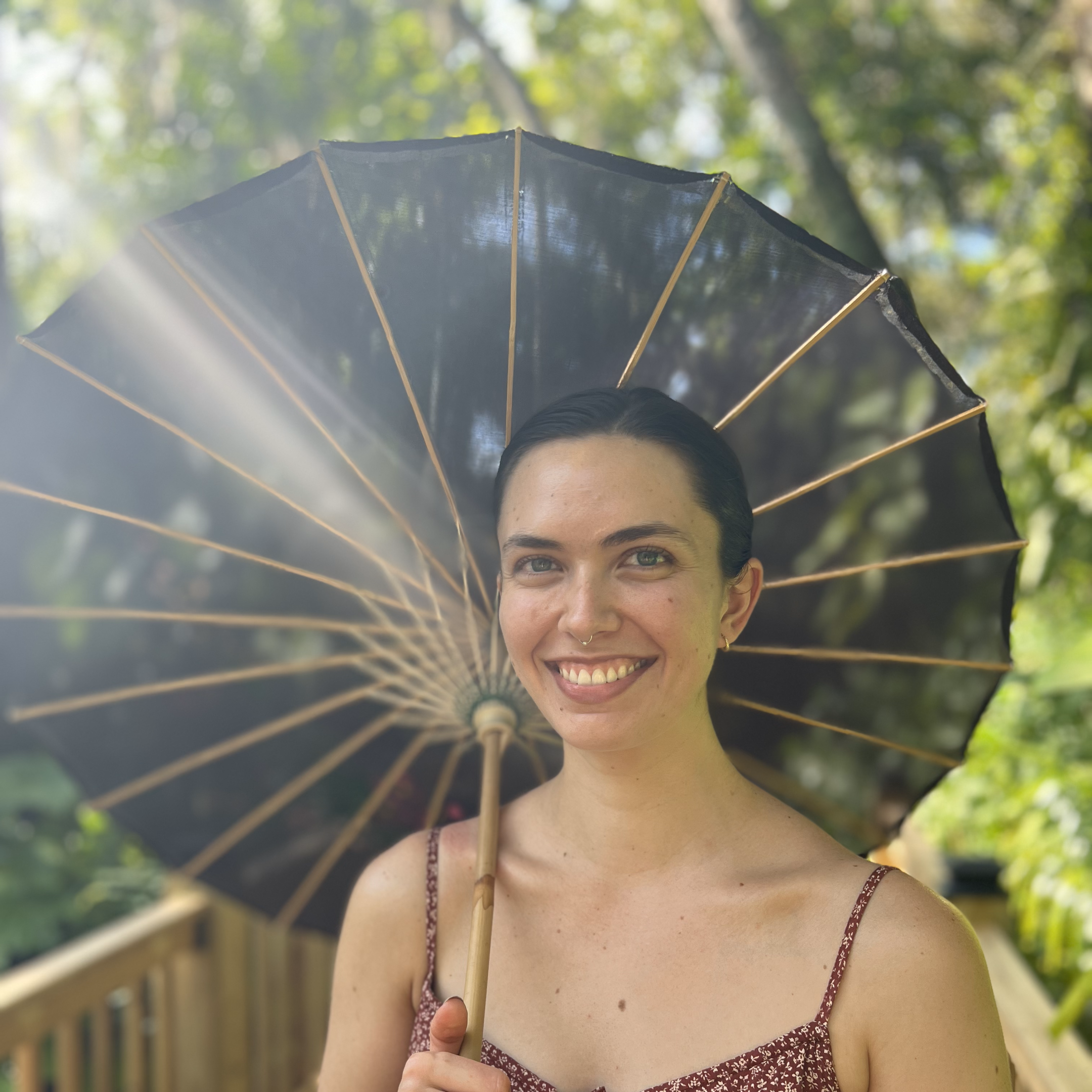 Close up photo of the author, Margot Emmeline, holding a black parasol.